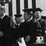 President John F. Kennedy shaking hands with the President of the University, William Friday, at the celebration of the University of North Carolina's University Day, October 12, 1961. Aycock, chancellor of the University stands on the other side of Kennedy. Henry Brandis, the dean of the Law School, stands behind and to the right of Friday. (1961)